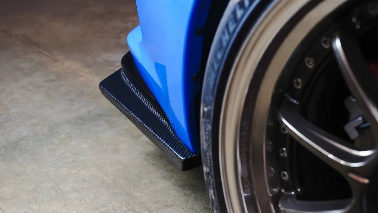 Close-up of a car wheel with a blue fender and black tire on a concrete floor.