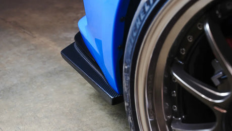 Close-up of a car wheel with a blue fender and black tire on a concrete floor.